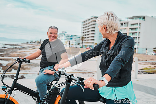 Image of Mature people, electrical or bike by ocean, beach or sea in bonding transportation, clean energy or sustainability travel. Ebike, electricity or eco friendly bicycle for happy couple or cycling woman