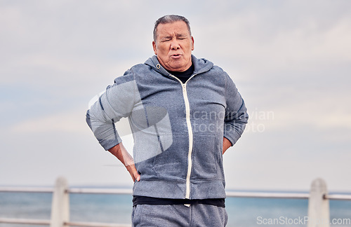 Image of Back pain, fitness and senior man outdoor at beach with scoliosis, sports wound and risk. Male runner, spine injury and joint problem of body muscle, first aid and health emergency at ocean promenade