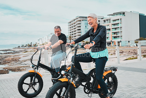 Image of Senior couple, electric bike and smile by the beach for fun bonding cycling or travel together in the city. Happy elderly man and woman enjoying cruise on electrical bicycle for trip in Cape Town