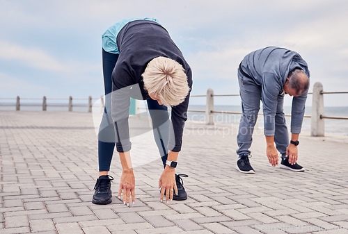 Image of Stretching, pilates and senior couple by ocean for exercise, healthy body and wellness in retirement. Sports, fitness and elderly man and woman start warm up for running, cardio workout and training