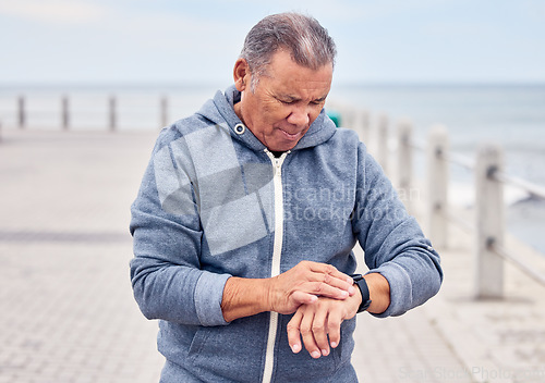 Image of Smart watch, senior man and fitness at outdoor beach promenade for exercise, training or workout. Stopwatch, sports male and runner check time, heart rate or monitor healthy body progress on data app