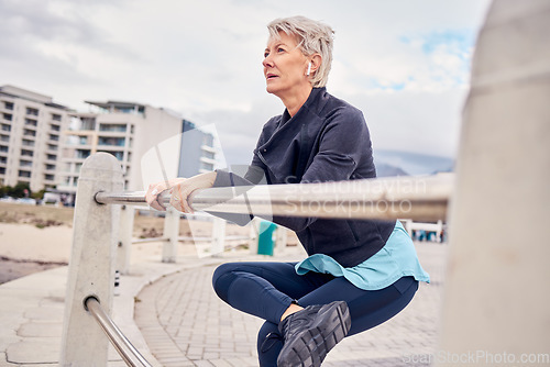 Image of Fitness, music and stretching with a senior woman getting redy for a cardio workout on the promenade. Exercise, warm up and running with a mature female athlete in preparation on an early morning jog