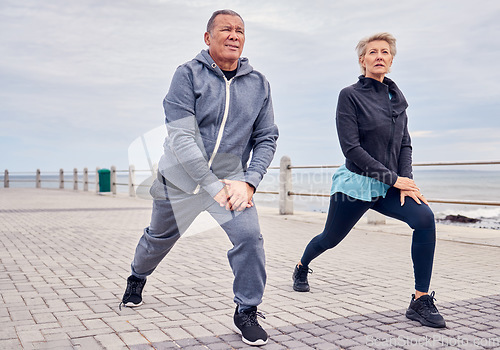 Image of Stretching legs, fitness and senior couple by ocean for exercise, healthy body and wellness in retirement. Sports, pilates and elderly man and woman ready for warm up, cardio workout and training