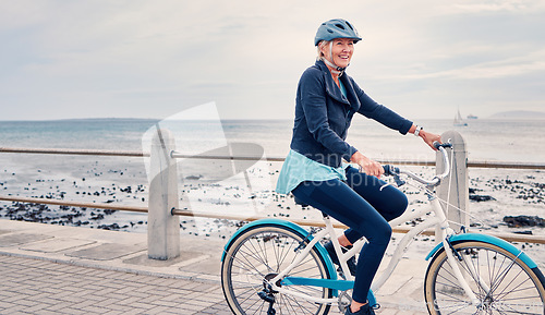 Image of Happy, smile and cycling with old woman at beach for fitness, peace and travel with blue sky mockup. Relax, workout and retirement with senior lady riding on bike for nature, health and wellness