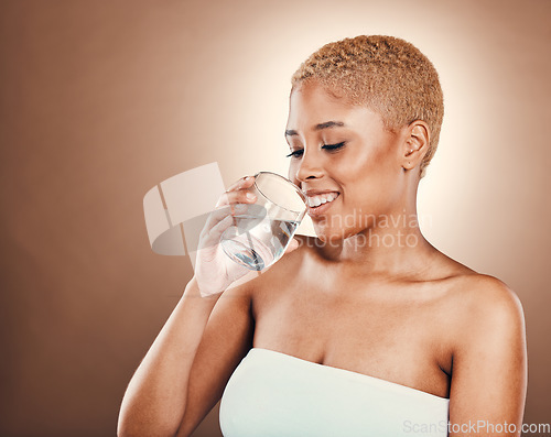 Image of Drinking water, black woman and glass for health on a brown background for skincare or diet. Aesthetic model person smile for clean and sustainable liquid for healthy lifestyle and wellness in studio