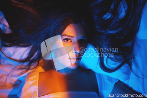 Image of Portrait, vaporwave lights and young woman face in bedroom with creative disco lighting. Makeup, beauty and model resting and feeling relax and calm on a bed pillow with cyberpunk aesthetic