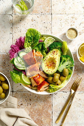 Image of Salmon avocado bowl with broccoli, olives and fresh salad. Healthy food, keto diet, top view