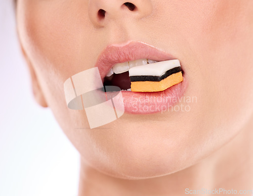 Image of Liquorice, woman eating and mouth with makeup and cosmetics in an isolated studio. White background, sweet food and candy product with hungry female model with cheat meal and sugar for dessert