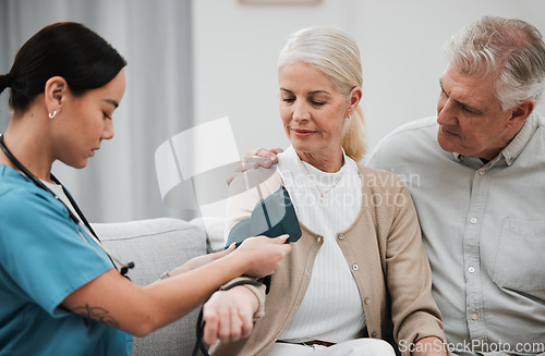 Image of Blood pressure, senior couple and nurse on a nursing home sofa for health and wellness check. Healthcare, doctor and living room consultation for medical test in retirement on a lounge couch