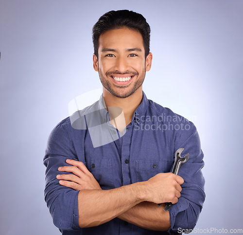 Image of Man, studio and portrait with tools or spanner for handyman, maintenance or repair work with a smile. Happy asian handy man person smile on purple background for engineer, mechanic or technician job