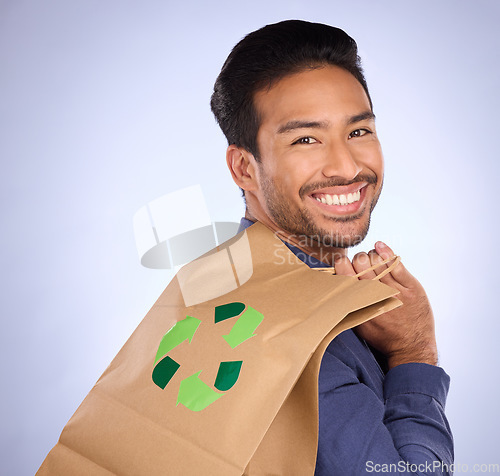 Image of Man in portrait, happy and recycling paper bag, environment and sustainable shopping on studio background. Eco friendly, green and climate change awareness in retail, sustainability and recycle logo