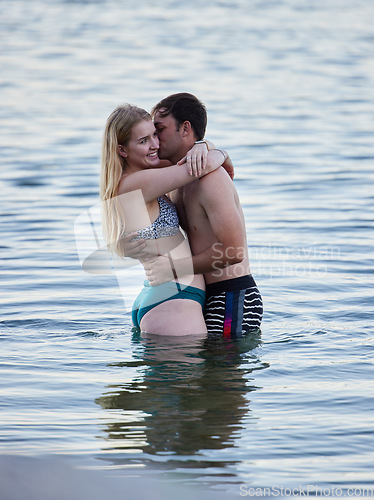 Image of Kiss, hug and couple swimming by the beach for bonding, quality time and holiday by ocean. Romance, happy and man and woman with affection, hugging and enjoying a swim together in the sea on vacation