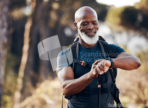 Image of Hiking, man and watch for time in nature forest trekking for fitness and cardio exercise. Senior black person smile while walking outdoor with backpack and smartwatch for travel, health and wellness