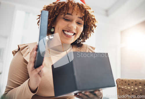 Image of Christmas, gift and celebration with a business black woman opening a box at an office party or event. December, holiday and present with a female employee holding a giftbox while feeling happy