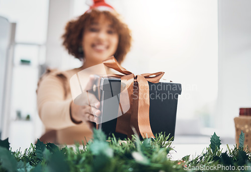 Image of Christmas, gift and celebration with a business black woman giving a box at an office party or event. December, holiday and present with a female employee holding a giftbox while feeling happy