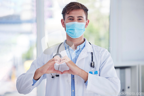 Image of Covid, portrait and doctor with hand heart sign at hospital for healthcare, innovation and symbol of trust. Emoji, hands and face of cardiovascular surgeon with mask for corona compliance at a clinic