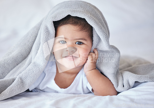 Image of Happy, comfy and portrait of a baby on a bed to relax, sleep and rest with a blanket. Smile, cute and adorable girl child lying in the bedroom for relaxation, comfort and happiness in a house