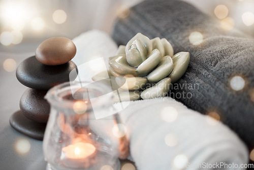 Image of Rock, candle and towel in a spa for zen to relax in a stress free empty room with aromatherapy ambience. Luxury, salon and wellness with still life objects in an interior for relaxing stress relief