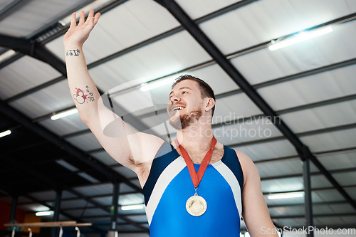 Image of Man, medal celebration and winning smile with wave, sports and hand in air at competition with pride. Champion athlete, happy and winner with gold, celebrate or success in global gymnastics contest