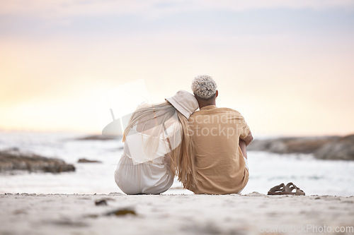 Image of Rear view of a young couple taking a break at the beach during sunset. Caucasian female and her mixed race boyfriend relaxing and enjoying the view at the beach