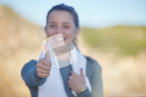 Image of Thumbs up, exercise and a sports woman on a blurred background outdoor for a cardio or endurance workout. Hand sign, fitness and running with a female athlete standing outside for health or wellness