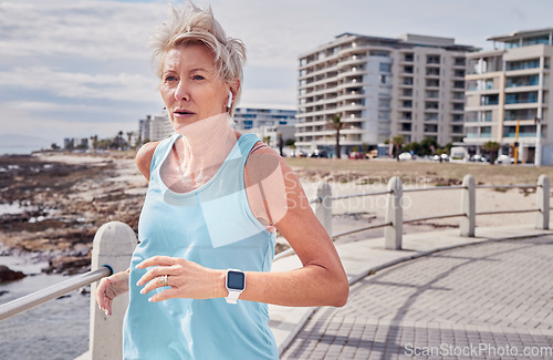 Image of Senior woman, fitness and running at beach promenade for energy, wellness and healthy workout in Miami. Elderly female, earphones and runner at sea for sports, cardio exercise and marathon training