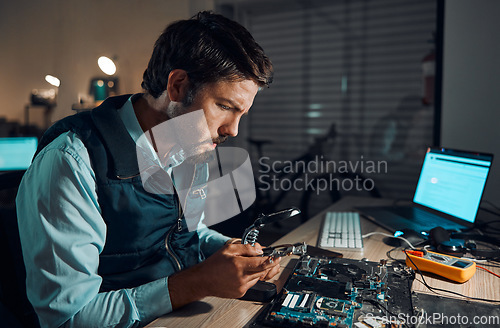 Image of Man, motherboard and magnifying glass at repair workshop in night for maintenance, computer tech or industry with focus. Technician, circuit and it job in dark with electronics, engineering and tools
