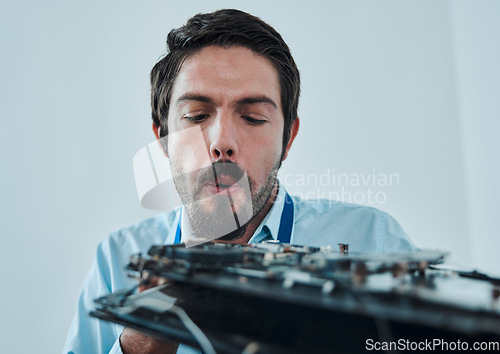 Image of Information technology, fixing motherboard circuit and man blow dust from electronics, semiconductor or computer hardware. CPU system maintenance, service industry face and IT worker repair microchip