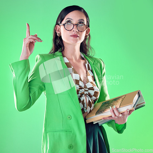 Image of Woman, books and teacher pointing up in studio isolated on a green background. Gen z, education and emoji gesture of smart female educator carrying textbooks for learning, studying and knowledge.