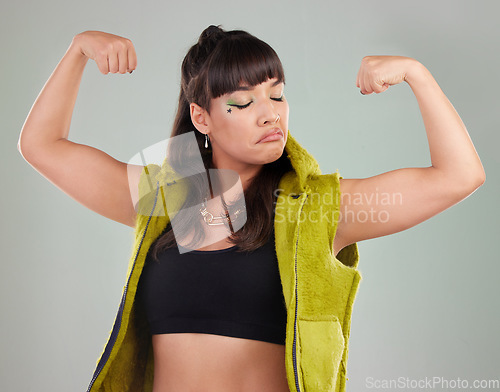 Image of Gen z, woman and flexing arms for empowerment, motivation and against grey studio background. Female, girl and show strength with freedom, winner and style with confidence, strong and trendy fashion