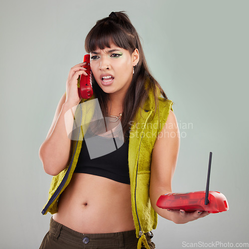 Image of Angry, problem and woman with a telephone for a conversation isolated on a grey studio background. Stress, frustrated and mad girl speaking on a vintage landline phone for communication and conflict