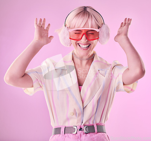 Image of Fashion, beauty and happy woman isolated on pink background excited, wow and dancing on creative aesthetic. Earmuffs, clothes and cool, retro and punk sunglasses of gen z model or person in studio