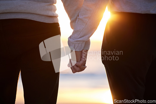 Image of Beach, couple and holding hands at sunset for love and trust or commitment and support on vacation. Hand of man and woman together on holiday at sea to relax, travel and connect in nature with care