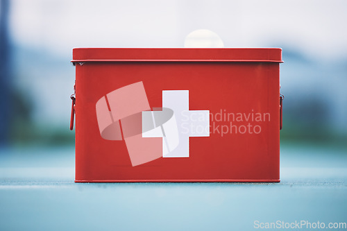 Image of First aid, box and medical equipment for health emergency, response and treatment kit isolated in a blurred background. Red, cross and safety or medicine on a table for fast healthcare or cure