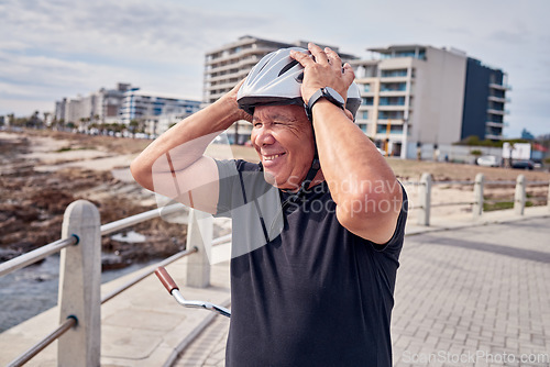 Image of Senior man, smile and helmet at the beach with bicycle for weekend, trip or holiday travel in Cape Town. Happy elderly male biker or cyclist smiling for cycling, journey or break by the ocean coast