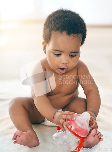 Image of Kids, black baby and girl with a bottle sitting on a blanket on the floor of a home for child development. Children, cute and curious with a newborn infant learning or growing alone in a house