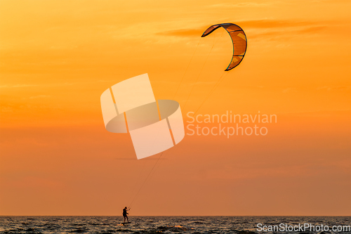 Image of Kiteboarding kitesurfing kiteboarder kitesurfer kites silhouette in the ocean on sunset