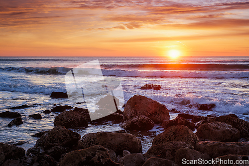 Image of Atlantic ocean sunset with waves and rocks. Costa da Caparica, Portugal