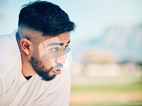 Image of Tired, breathing and sports man at a field for training, break and breathing exercise on blurred background. Athletic, sports and indian guy stop to breathe after exercise, workout or match practice