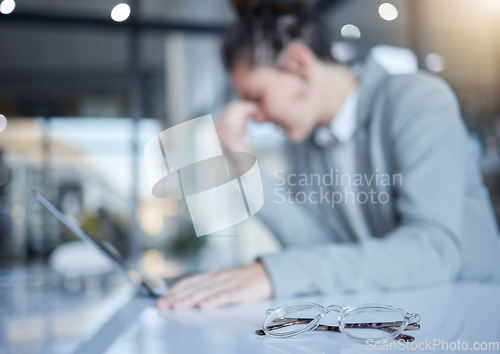 Image of Woman, headache and glasses in office with laptop, blurred background and space for mockup with stress. Burnout, eye care problem and overworked girl with computer, pain and frustrated in workplace