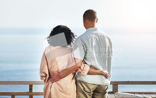 Image of Back, view and senior couple by beach, hug and enjoying quality time on holiday or vacation. Love, care and retired elderly man and woman hugging, embrace or cuddle while having fun by ocean or sea.