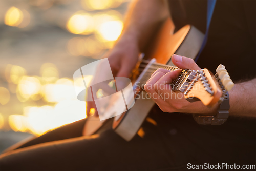 Image of Street musician playing electric guitar hands close up