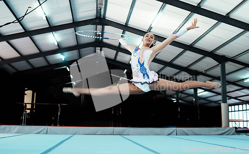 Image of Gymnastics, woman athlete and performance at gym, fitness and leap, legs stretching and in the air with flexibility. Exercise, competition and professional female gymnast with sports and hula hoop