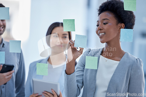 Image of Black woman, writing and planning schedule with team on glass board for brainstorming meeting at office. Happy African American female in teamwork collaboration, tasks or sticky note for project plan