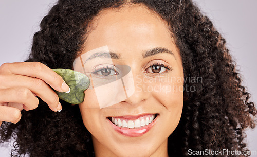 Image of Face skincare, portrait and black woman with gua sha in studio isolated on a gray background. Dermatology, cosmetics and happy female model with tool, stone or crystal for healthy skin and wellness.