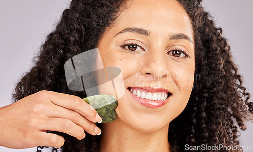 Image of Skincare, face portrait and black woman with gua sha in studio isolated on a gray background. Dermatology, cosmetics and happy female model with tool, stone or crystal for healthy skin and wellness.