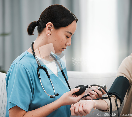 Image of Blood pressure, Asian nurse and patient in a nursing home sofa for health and wellness check. Healthcare, doctor and living room consultation for medical test in retirement on a lounge couch