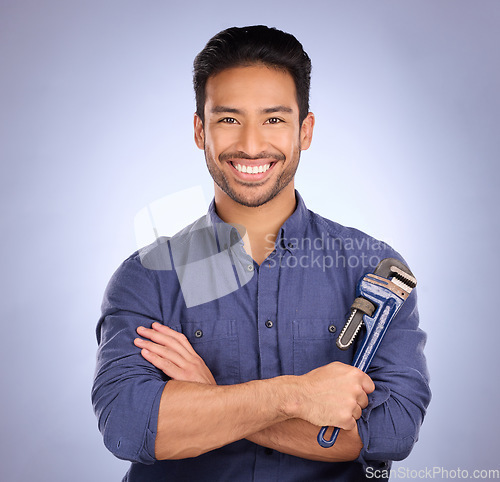 Image of Man, studio and portrait with tools or wrench for handyman, maintenance or repair work with smile. Happy asian model person on blue background with spanner for engineer, mechanic or technician job