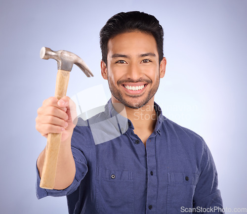 Image of Construction, showing and portrait of an Asian man with a hammer isolated on a studio background. Building, happy and builder with a tool for repairs, maintenance and handyman work on a backdrop