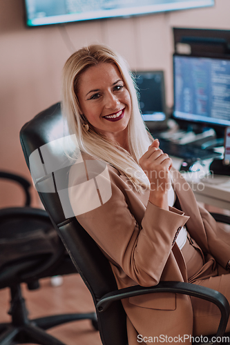 Image of A businesswoman sitting in a programmer's office surrounded by computers, showing her expertise and dedication to technology.